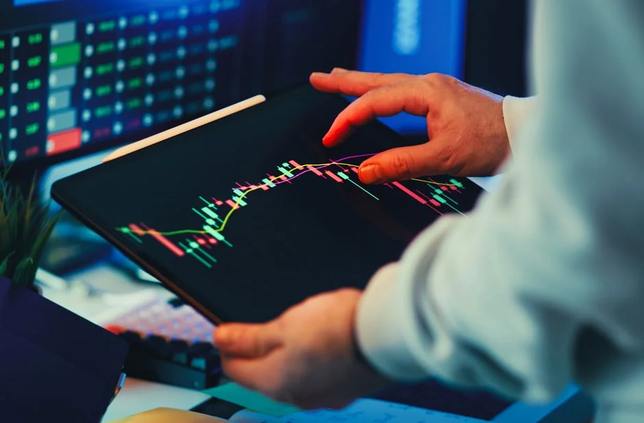 Équipe examinant des graphiques financiers et des données numériques sur des tablettes dans un environnement de bureau.